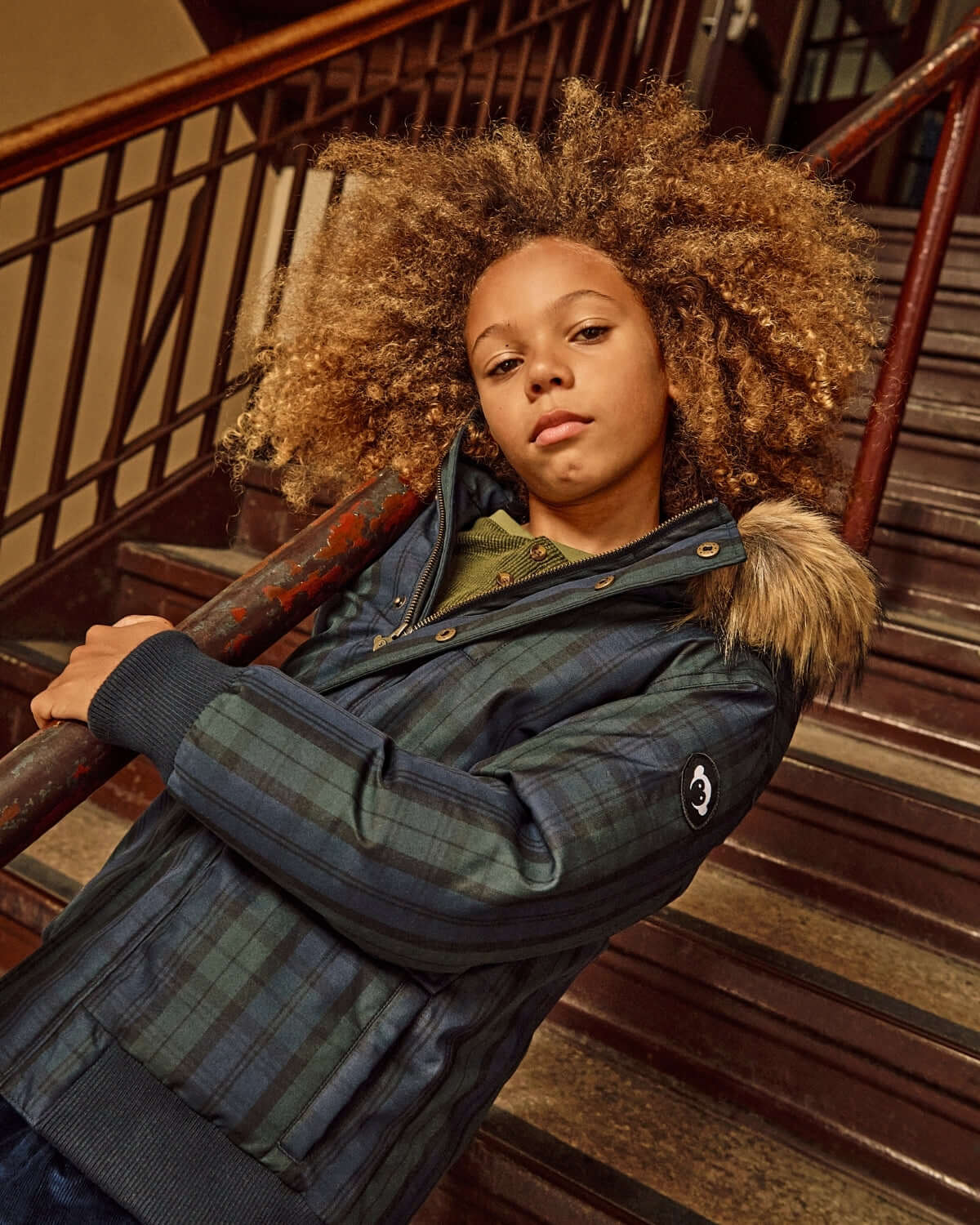 Black Watch Tartan City Transit Coat worn by a child on stairs with fur-lined hood and stylish design.