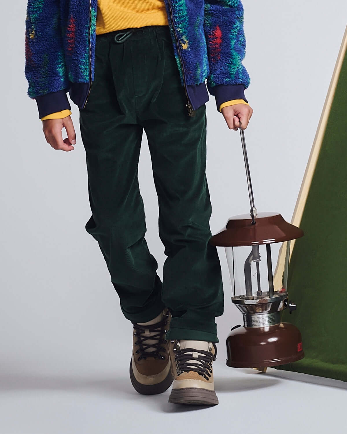 Child wearing Spruce Club Pants while holding a vintage lantern, showcasing comfort and adventure-ready style.