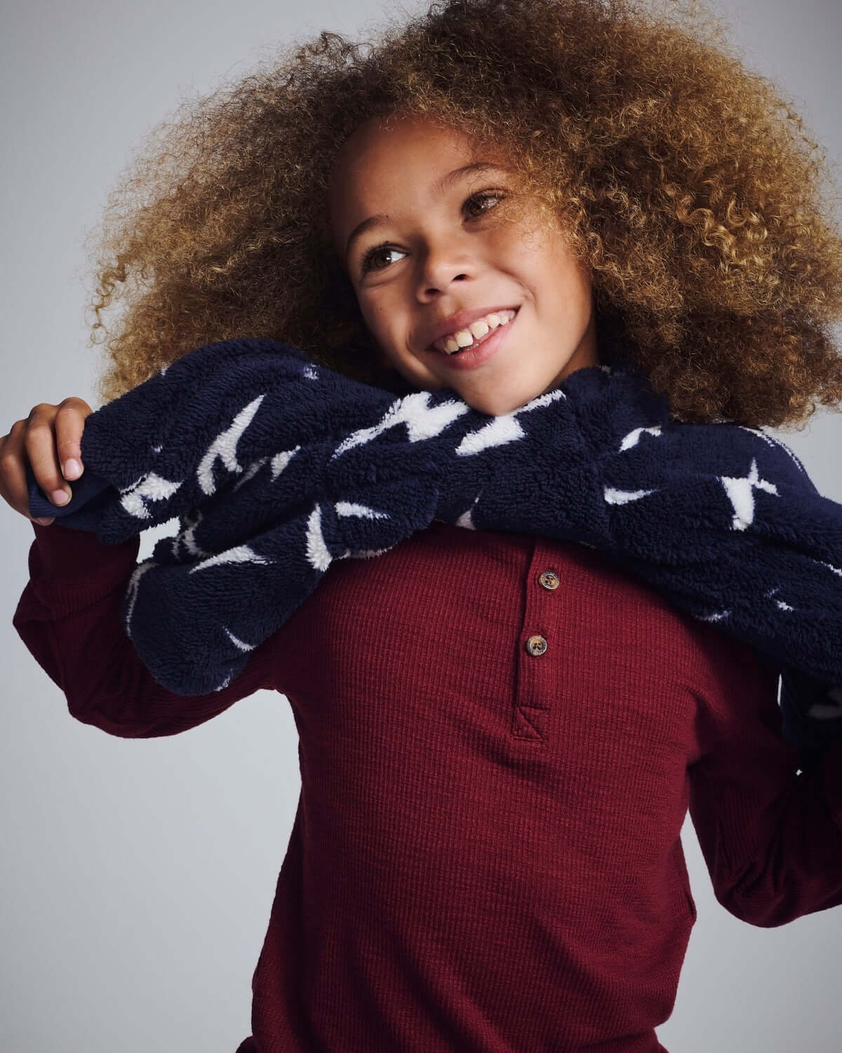 Child wearing Dark Cherry Craftsman Thermal Henley, smiling with a soft navy scarf around their shoulders.