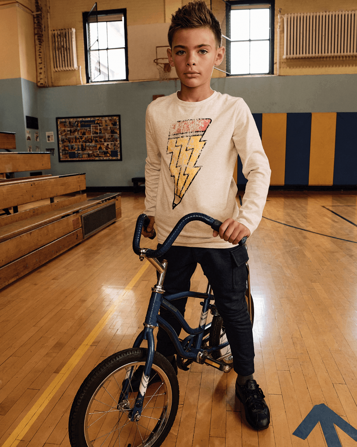 Creative Spark Graphic Long Sleeve Tee on a child riding a bike in a gym setting.