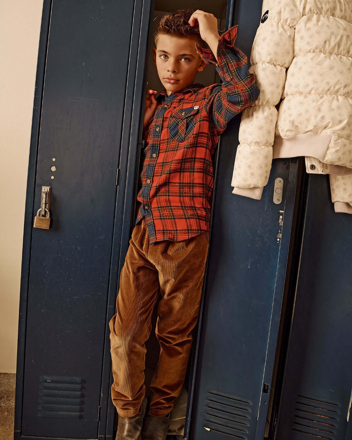 Child in Holiday Plaid Flannel Shirt standing beside school lockers, showcasing casual style with a cozy and trendy look.