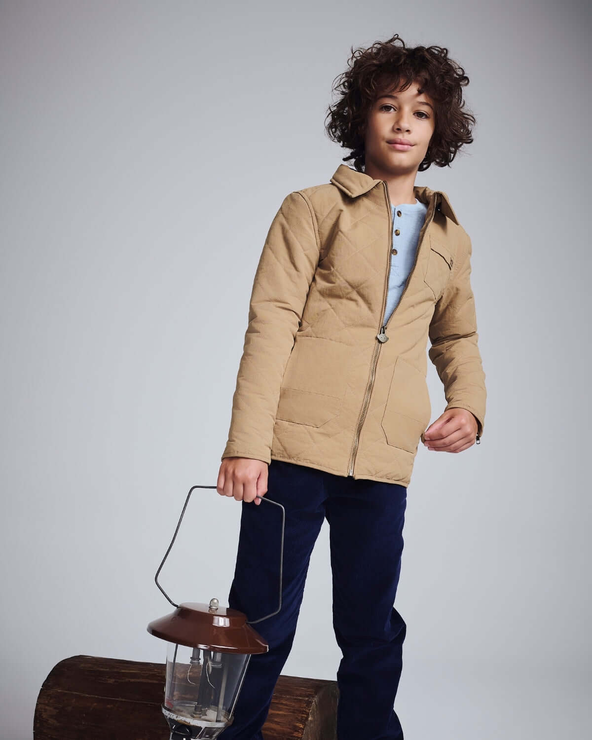 Boy wearing a Khaki Flight Jacket holding a lantern, showcasing cozy and stylish outdoor fashion.