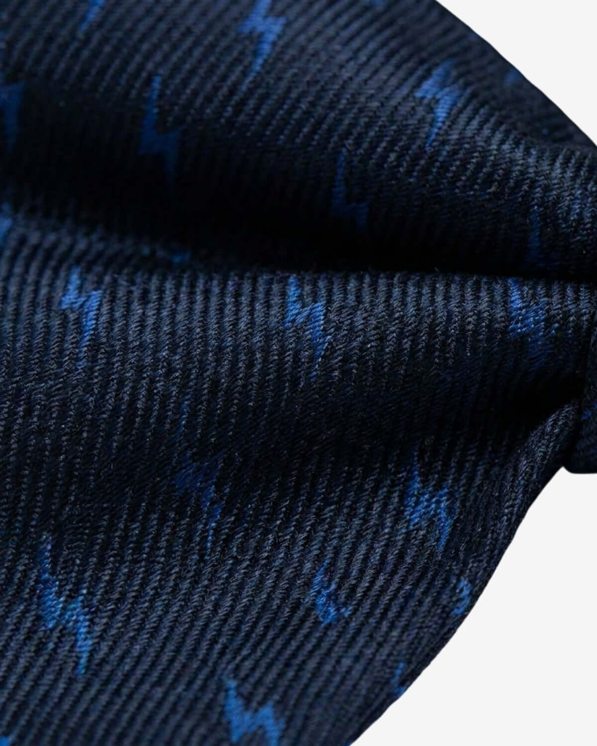 Close-up of a dark blue fabric with small white patterns on a white background