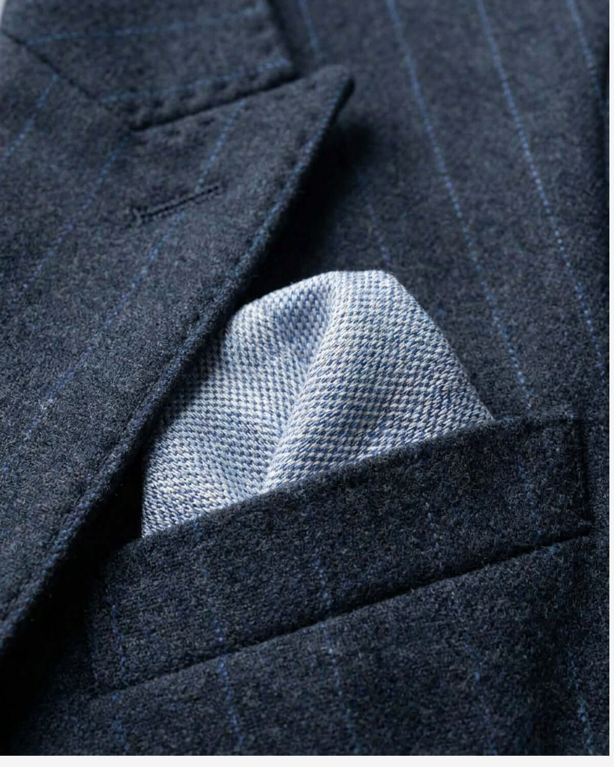 Close-up of a dark blue pinstripe suit with a light blue pocket square.