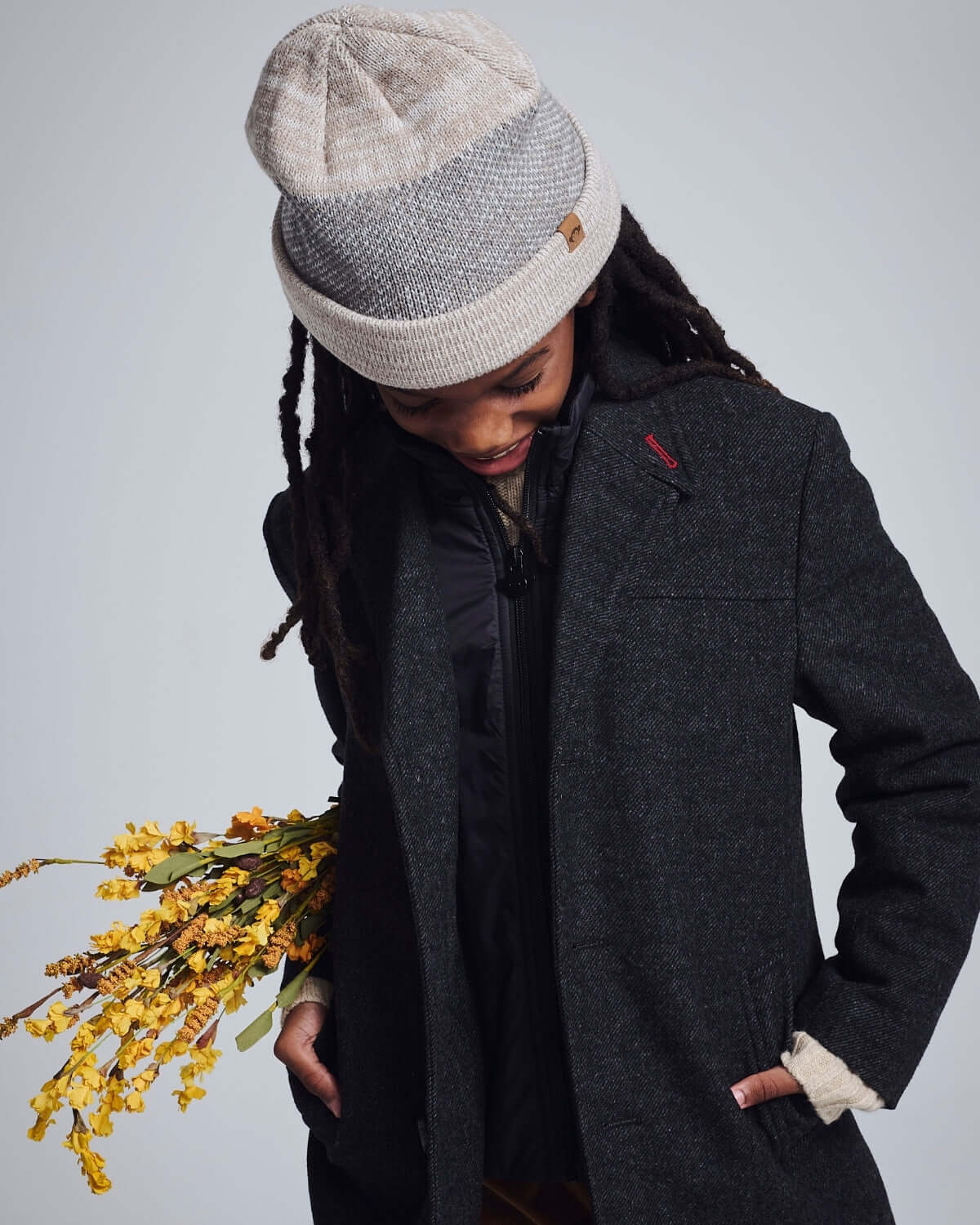 Child wearing the Heather Oatmeal Levi Hat, holding flowers, dressed in stylish outerwear.