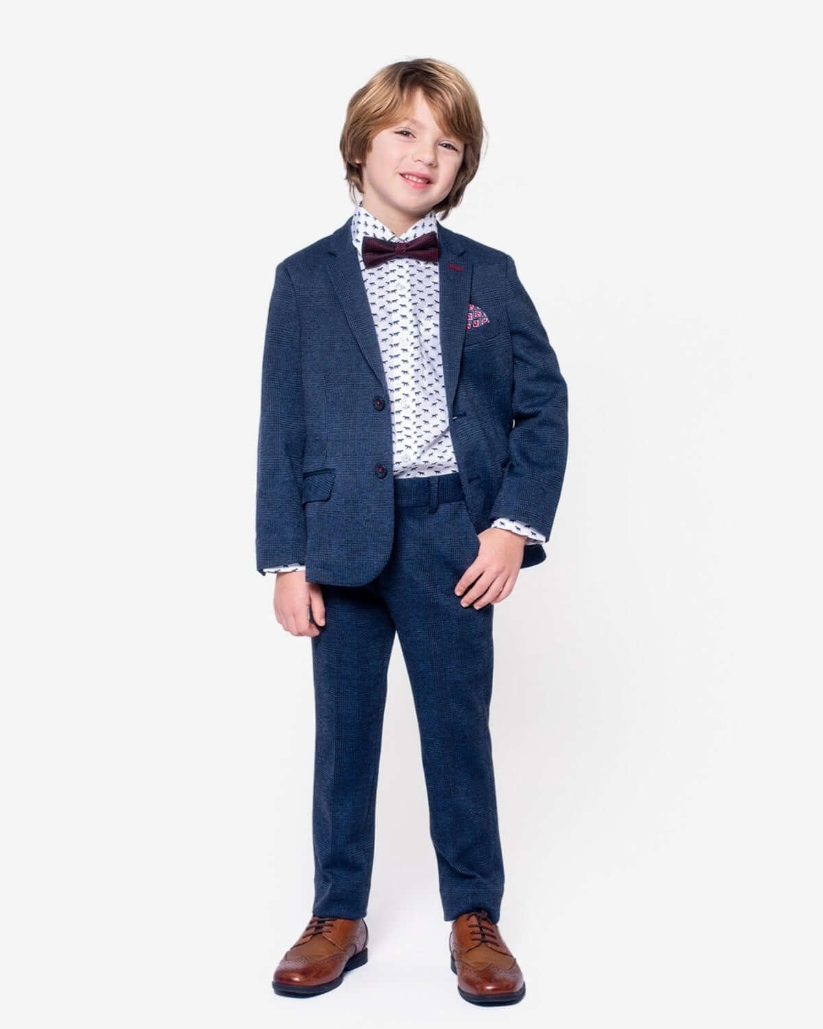 A young boy wearing The Pointer Standard Button Down dress shirt with a suit and bow tie, showcasing a playful style.