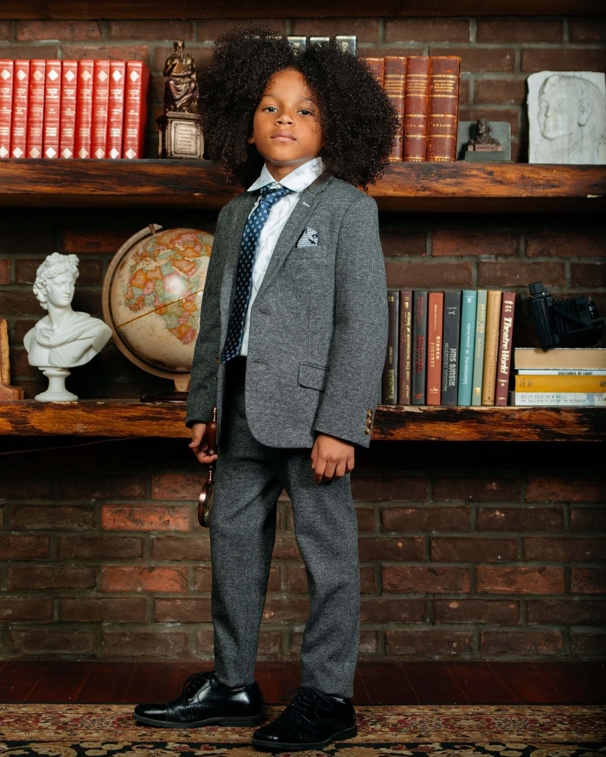Noir Micro Plaid Stretchy Mod Suit worn by a child with curly hair, posing in a stylish room.