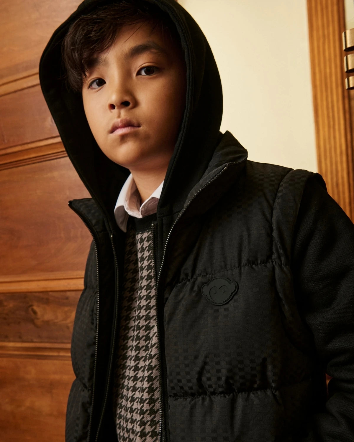 A boy wearing a black hooded puffer jacket. Appaman Fall/Winter 2026 collection.