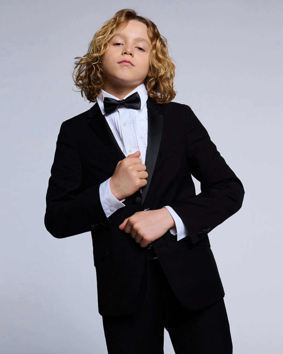 Black Tuxedo Suit Jacket worn by a young boy with a bow tie, perfect for formal events.