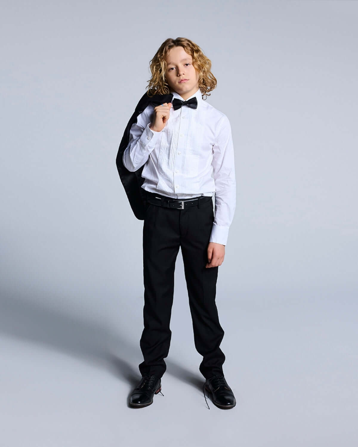 Young boy wearing a White Tuxedo Shirt with a bow tie, ready for formal events.