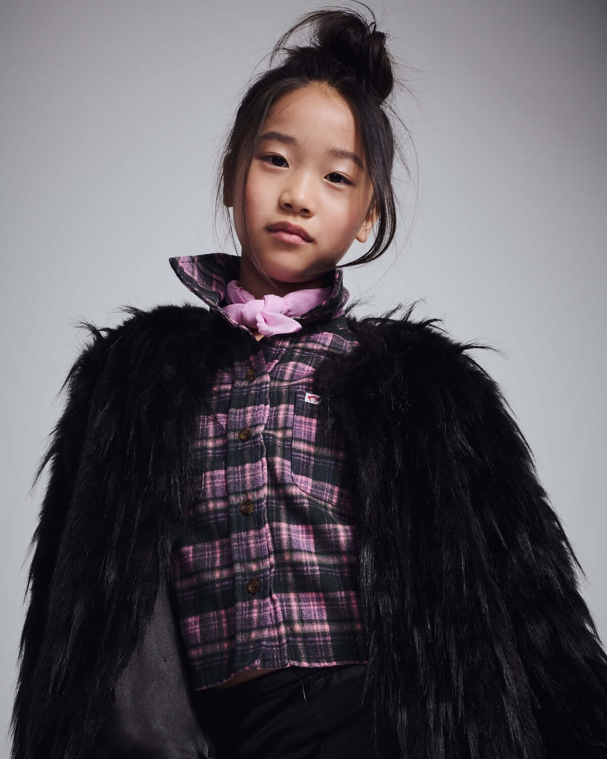 Black Faux Fur Coat worn by a young girl, showcasing a cozy and stylish look with a plaid top underneath.