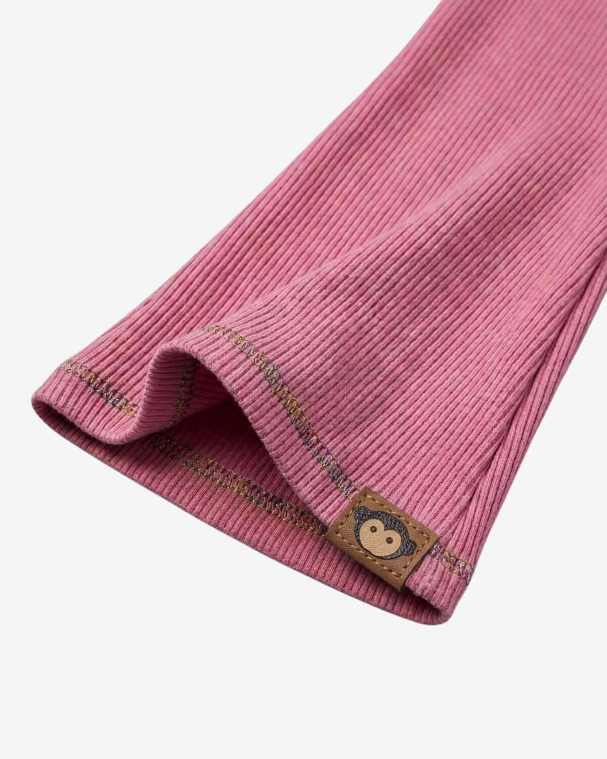 Close-up of a pink ribbed fabric with a brown label featuring a bear design on a white background.