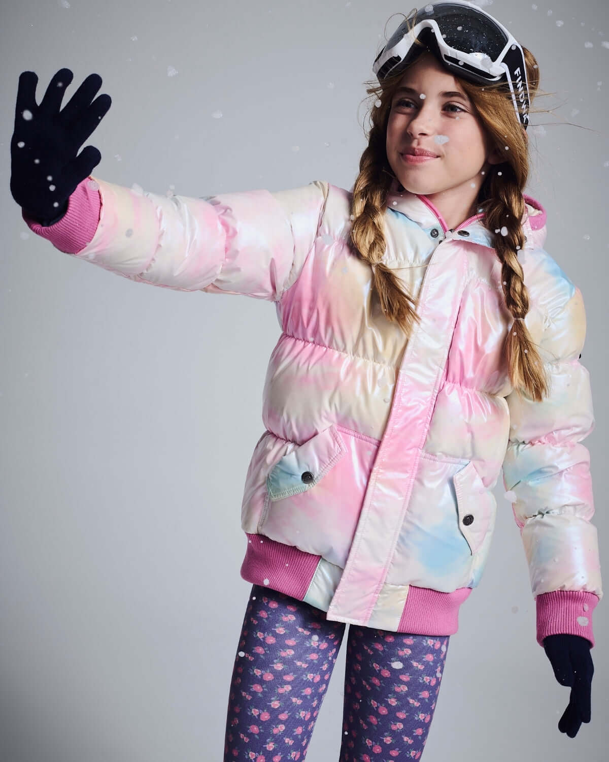 Girl wearing a colorful puffer jacket and Navy Primrose Leggings, enjoying a snowy day outdoors.