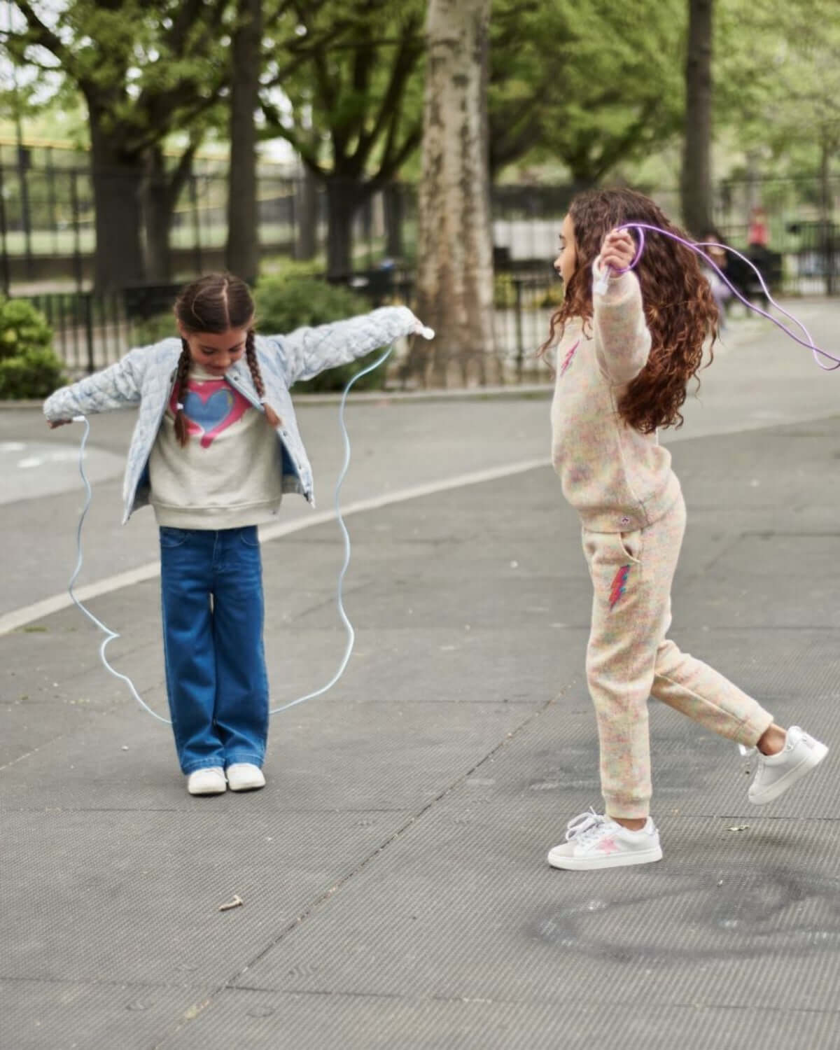 Two girls playing jump rope, wearing stylish outfits showcasing the Medium Wash Liana Pant.
