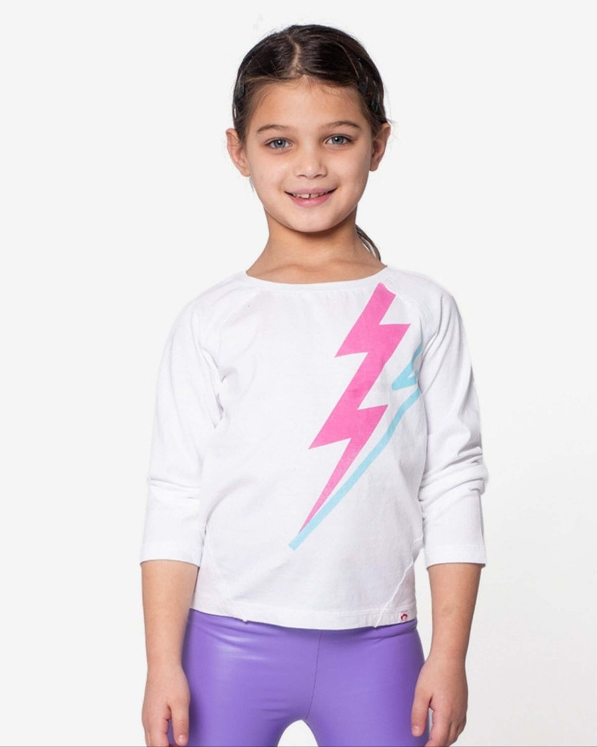 Lightning Bolt Adler Tee featuring a girl wearing a white top with a colorful lightning bolt design.