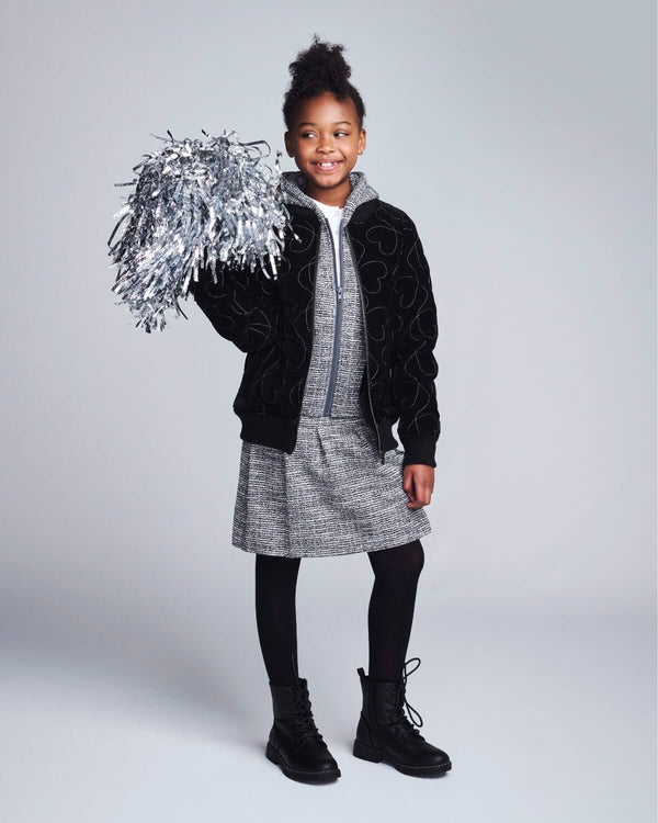 Girl wearing Silver Hearts Bomber Jacket, posing with silver pom-pom, stylish and ready for outdoor fun.