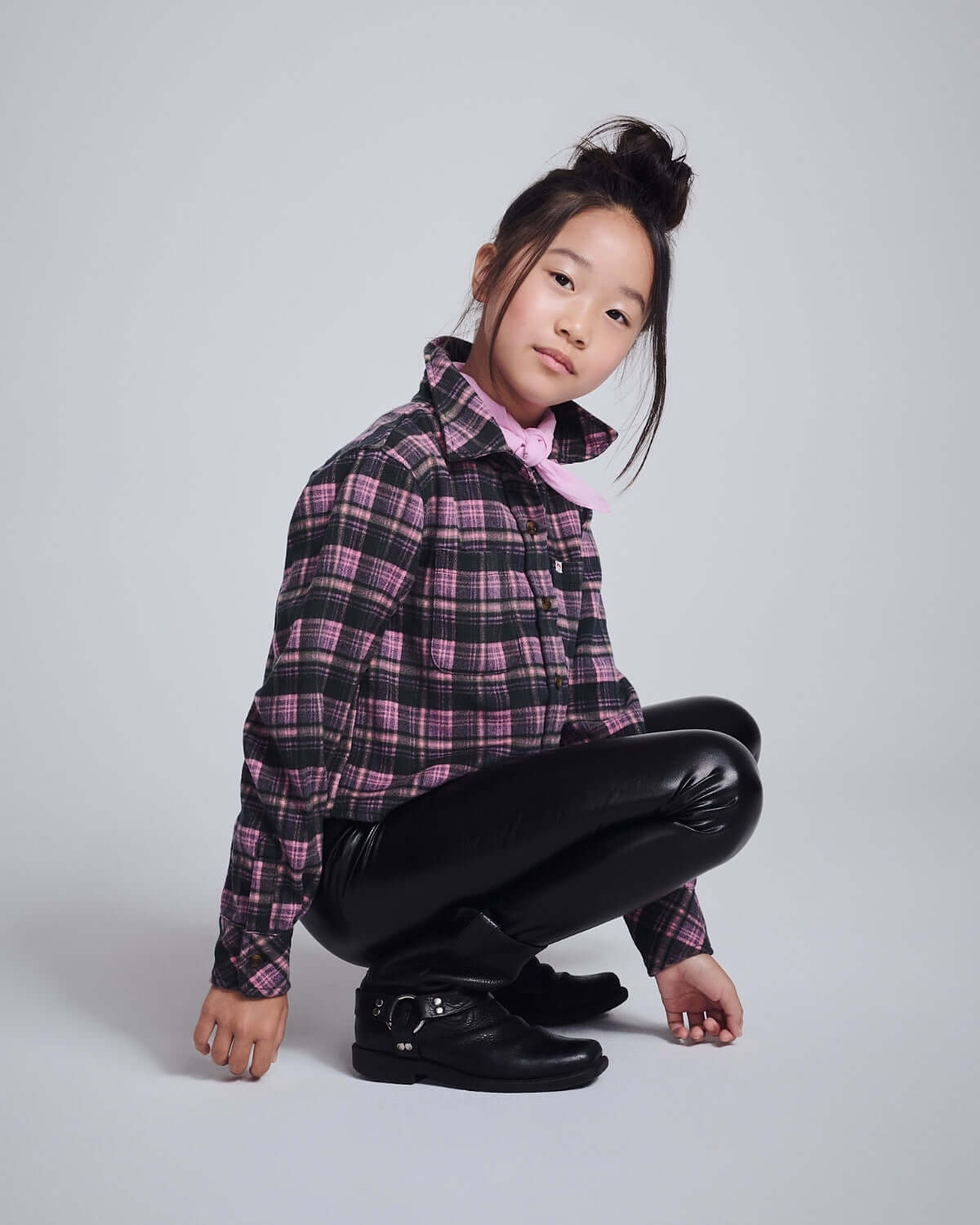 Pink Plaid Polly Cropped Flannel styled on a girl in a crouched pose, featuring a classic collar and playful plaid design.