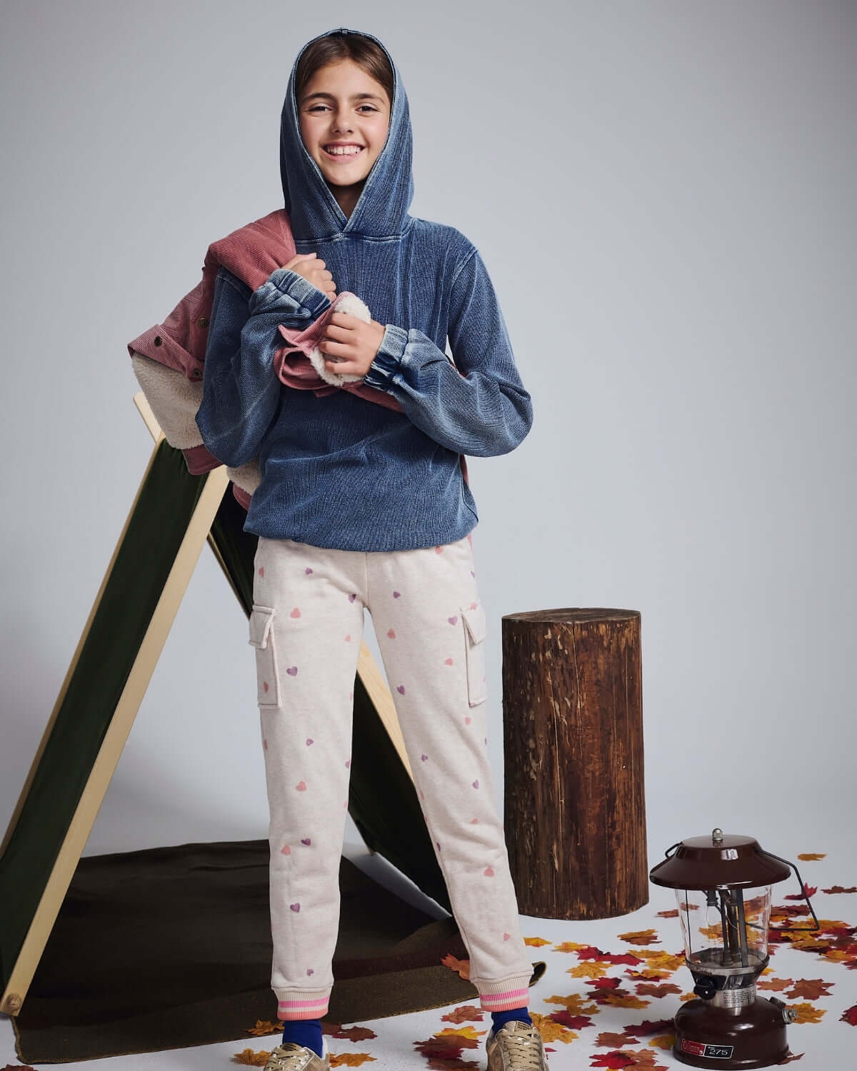 Child wearing Dusk Blue Pullover Hoodie with casual pants, smiling in a cozy fall setting.