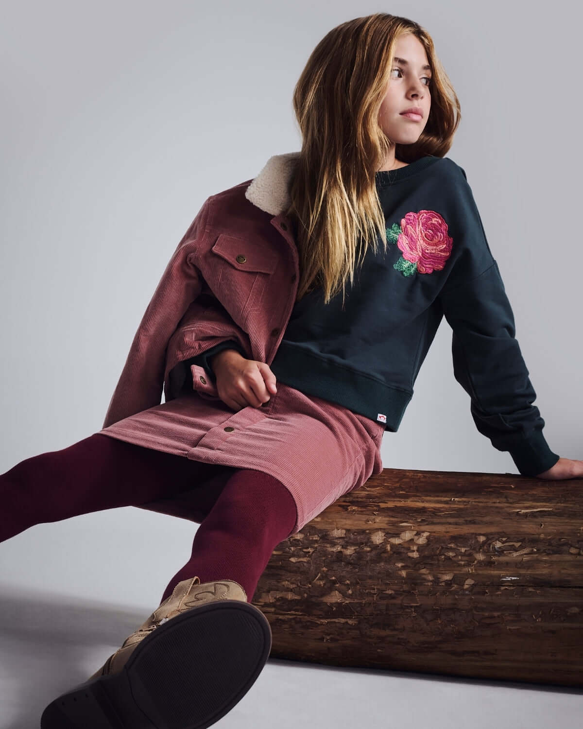 Rose Lisa Cropped Sweatshirt worn by a girl, featuring a pink rose detail, styled with a skirt and jacket.