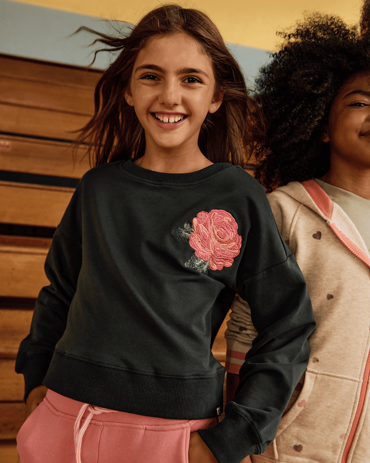Girl smiling in Rose Lisa Cropped Sweatshirt with pink rose detail, perfect for kids' stylish outfits.