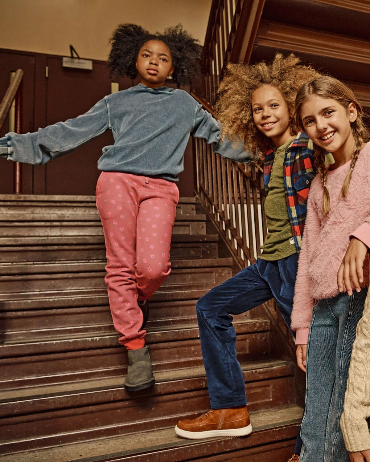 Girls wearing casual outfits on stairs, featuring Rose Quartz Stanton Joggers and playful styles.