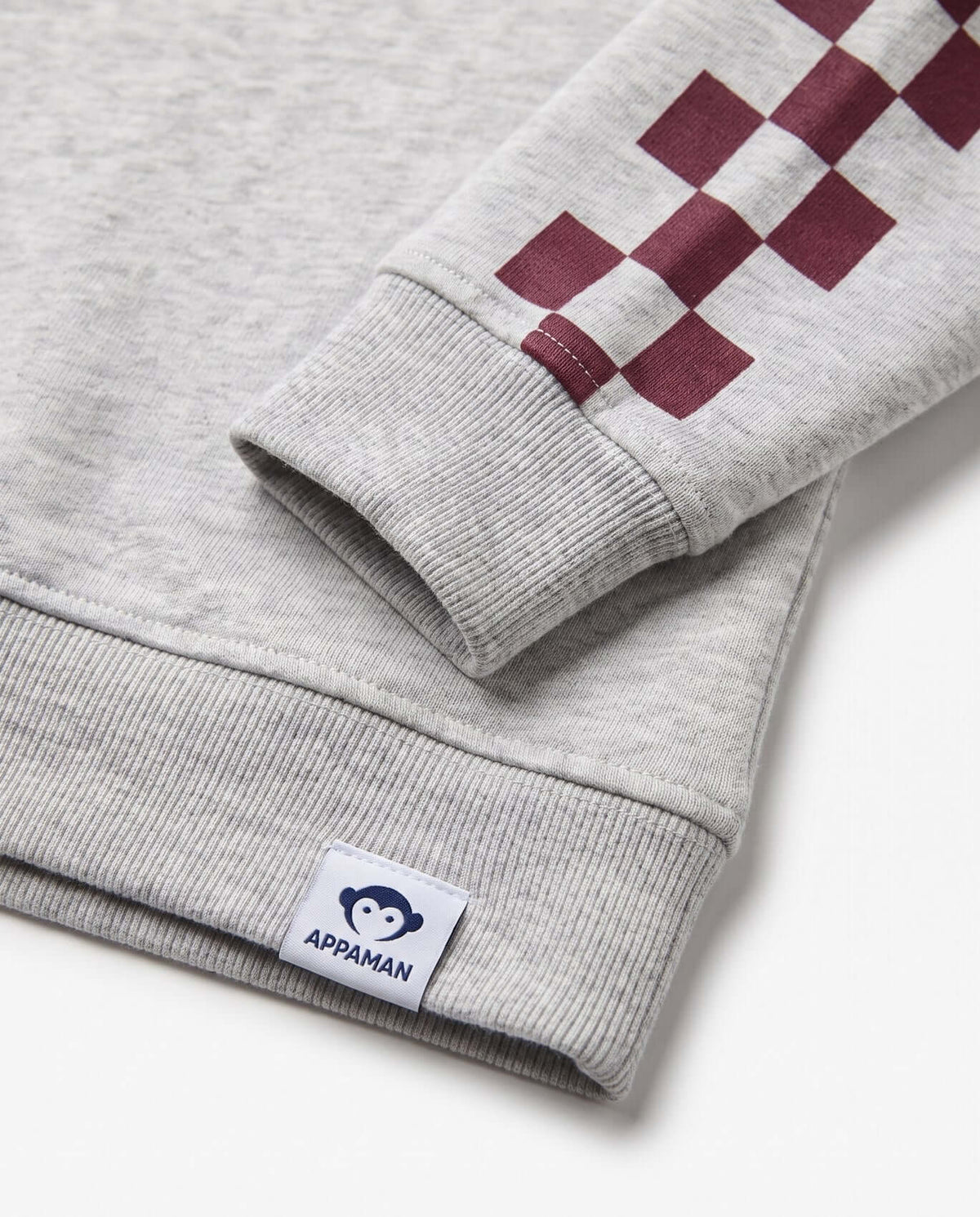 Close-up of Appaman's Oatmeal Tunic Hoodie sleeve with checker design and logo detailing.