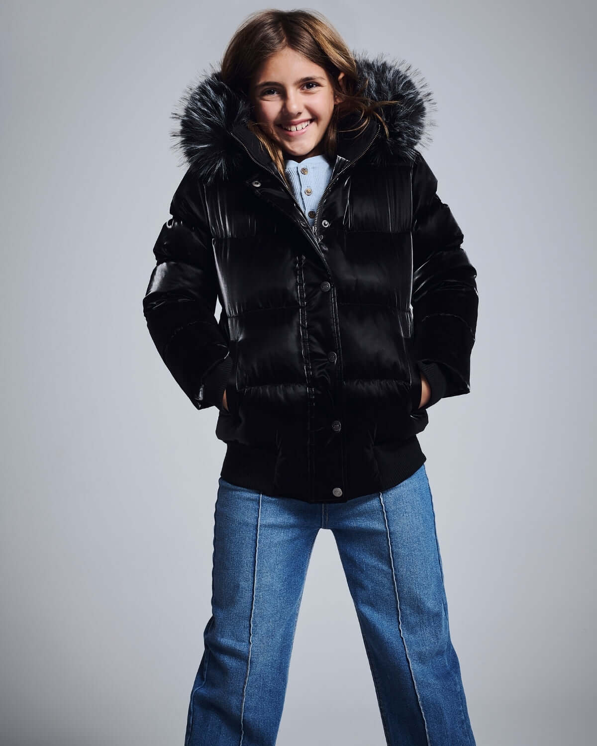 Girl smiling in a stylish black puffer jacket with fur hood, paired with Medium Wash Wide Leg Jeans.