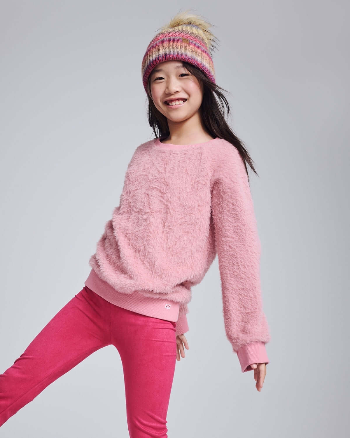 Girl wearing the Ivy Rose Willow Top, a cozy fuzzy pink top paired with pink leggings, perfect for chilly days.
