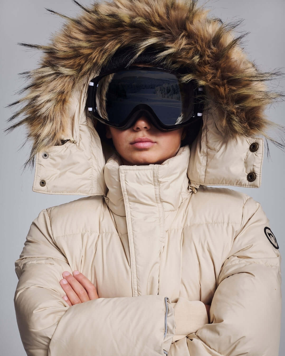 Ivory Expedition Puffer Coat with luxe faux fur hood and ski goggles for ultimate winter protection.