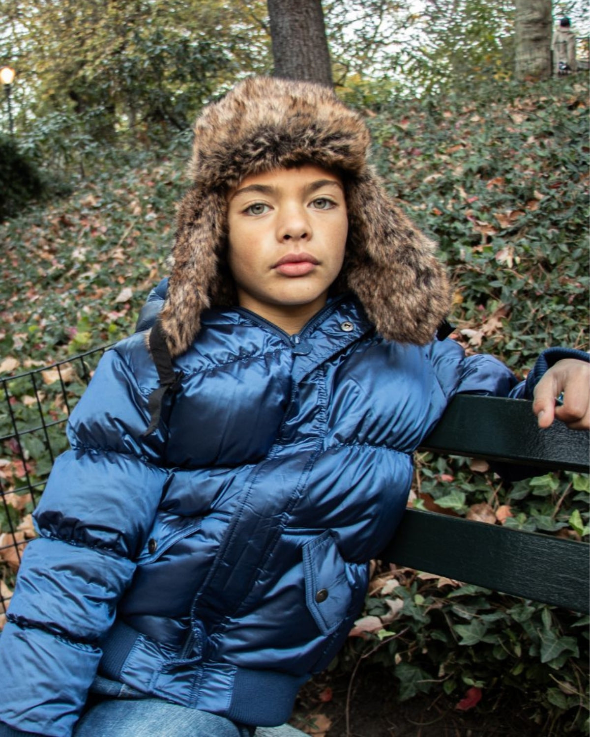 Stylish boy wearing a blue puffer jacket and a cozy faux fur-lined Benji Hat, ready for winter adventures in kids clothes.