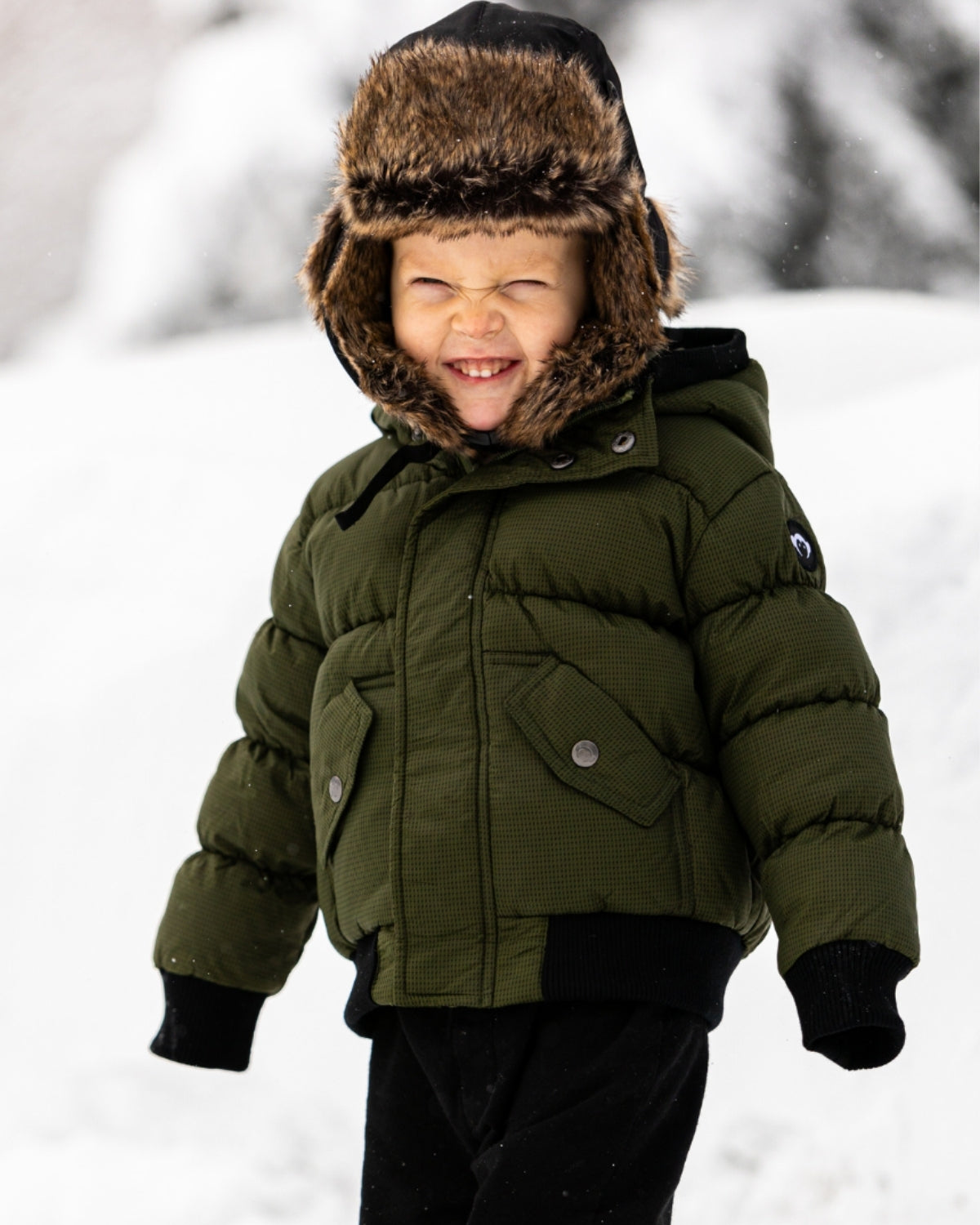 Smiling boy in a cozy green puffer jacket with faux fur hood, ready for winter adventures in style. Perfect for kids' back to school!