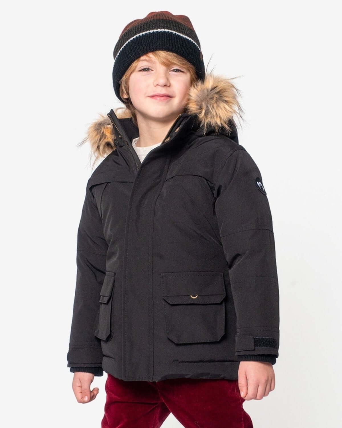 Stylish kid rocking a cozy black winter jacket and a fun hat, ready for snowy adventures!