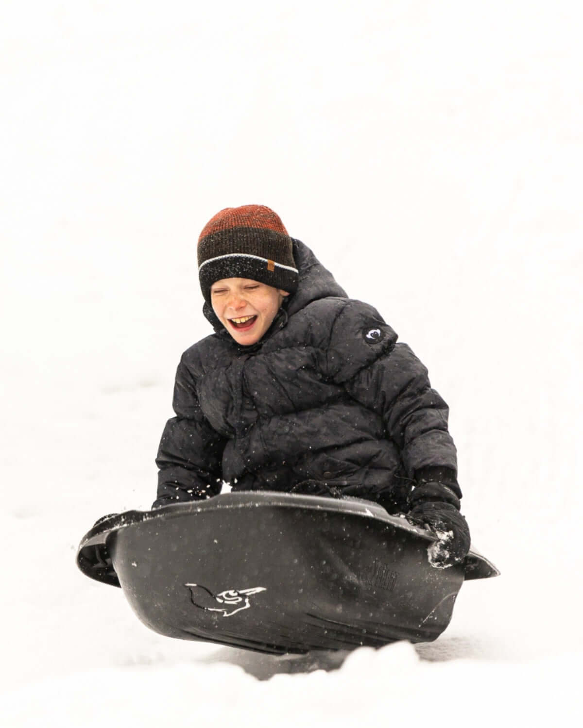 A joyful kid sledding in winter gear, showcasing playful moments in durable kids clothes for exciting back-to-school adventures!