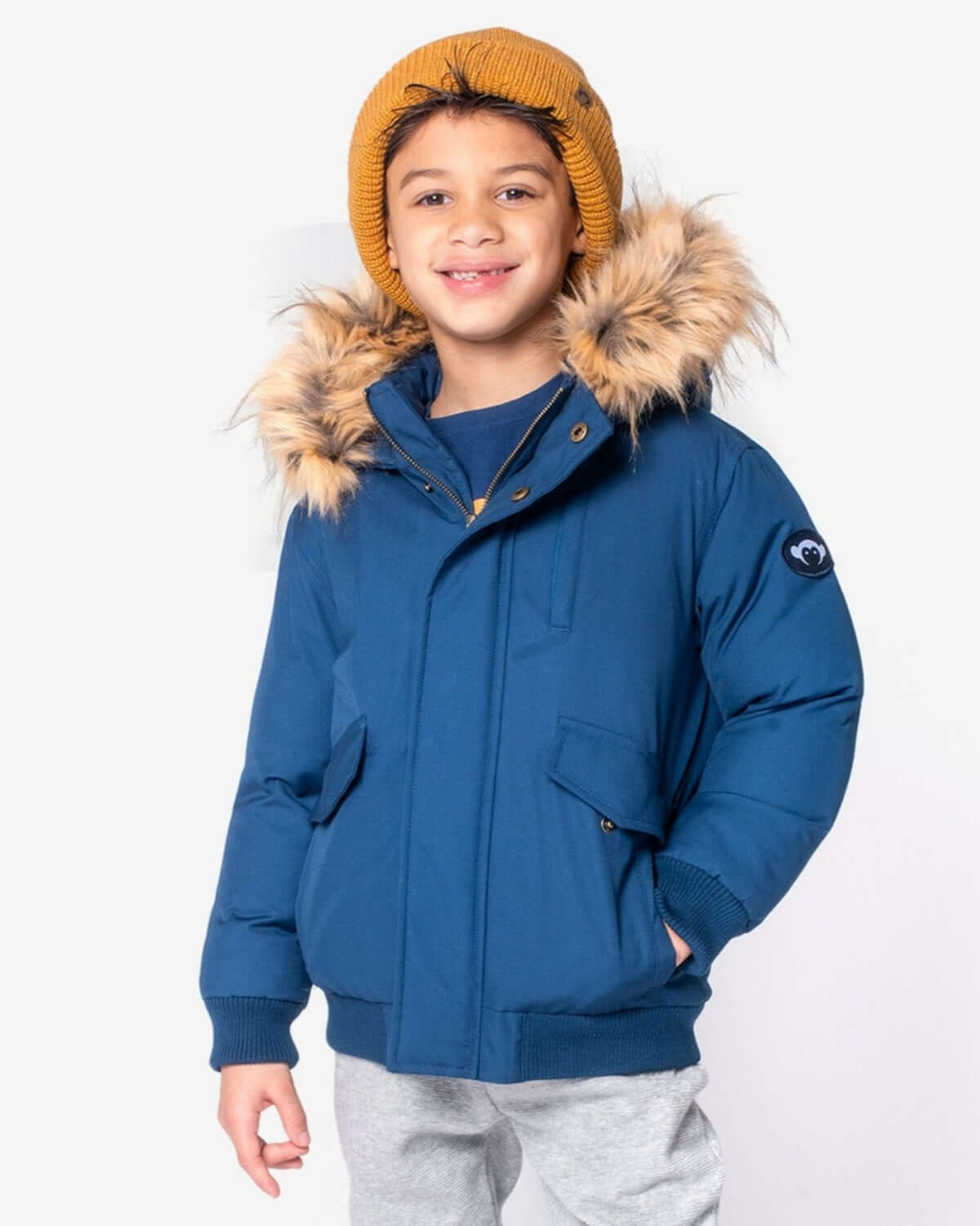 Stylish kid in a navy blue puffy jacket with a cozy fur-lined hood, ready to take on the chill in high-quality kids clothes.