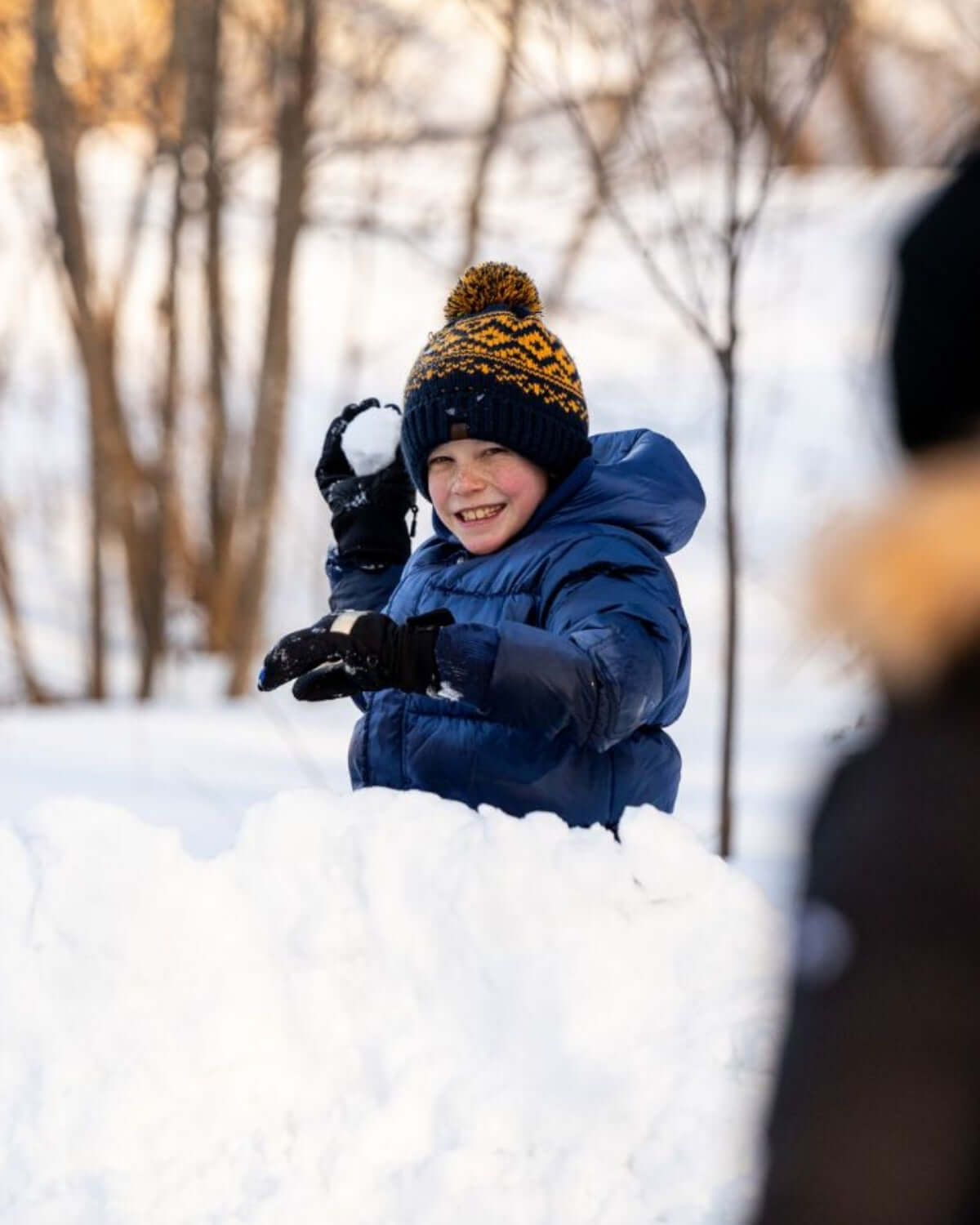 Happy child wearing a Navy Blue Bush Hat playing in the snow during winter. Perfect for cozy winter style!