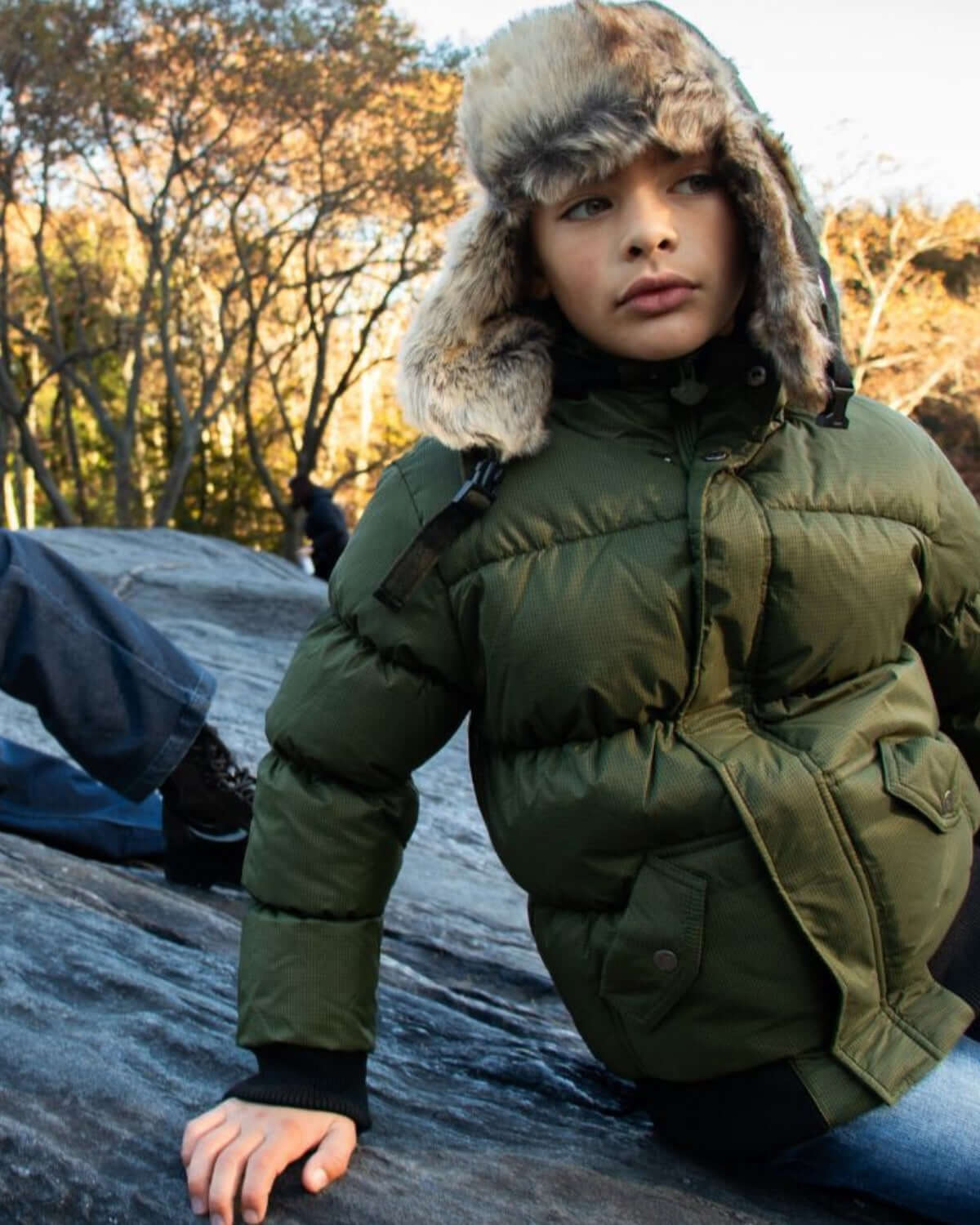 Cool kid rocking an olive puffer jacket with faux fur, ready for winter adventures in high-quality kids clothes.