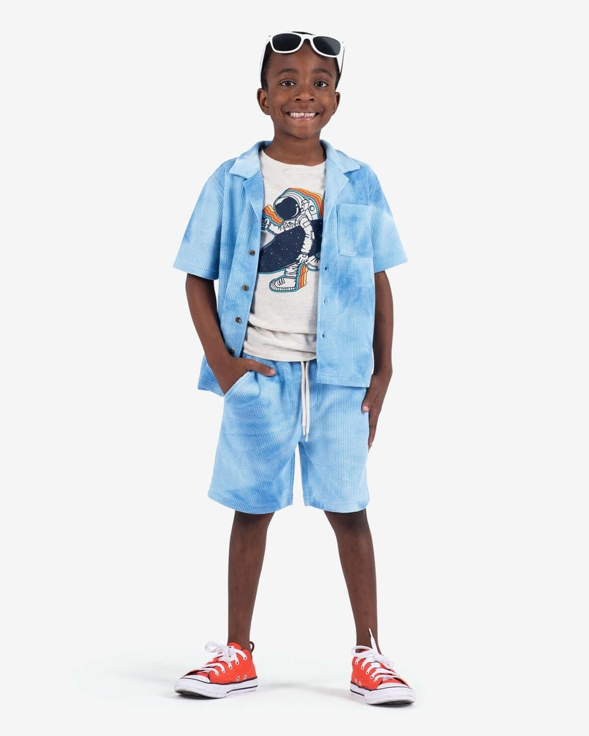 Stylish boy in blue tie dye resort shorts and matching shirt, ready for summer fun—kids clothes that blend comfort and chic!