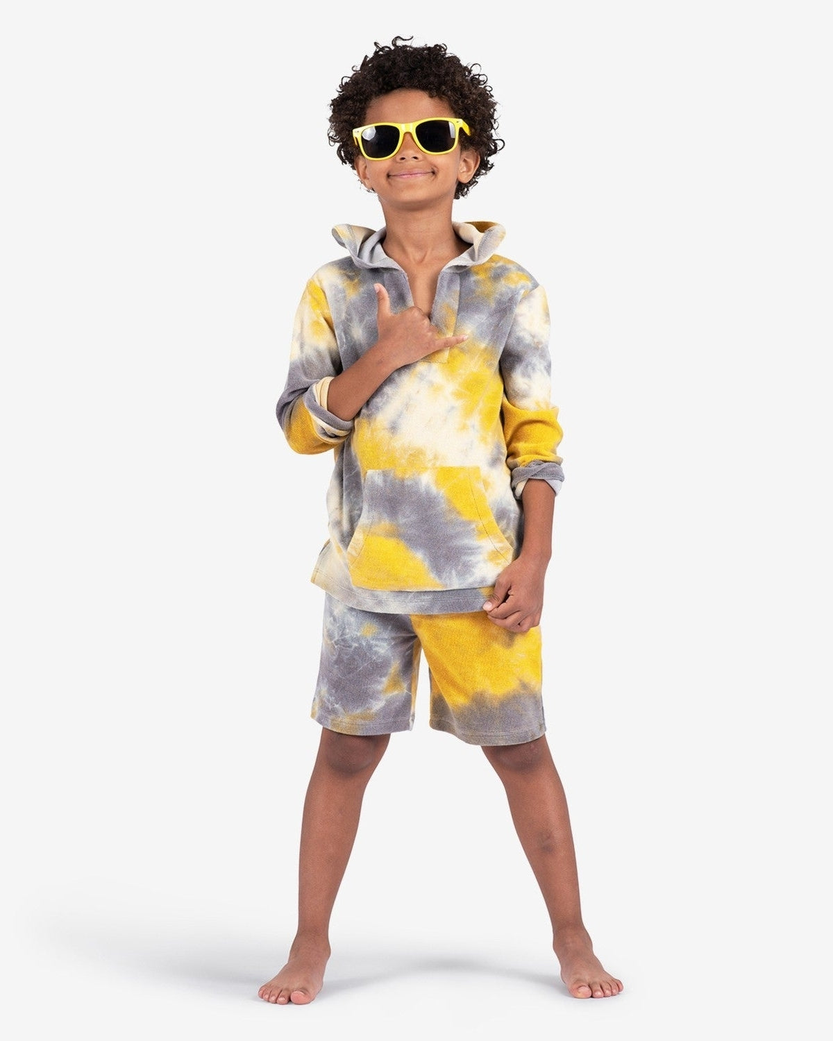 Stylish kid rocking the Goldenrod Preston Shorts and Baja Pullover, ready for fun in vibrant tie dye, sunglasses on!