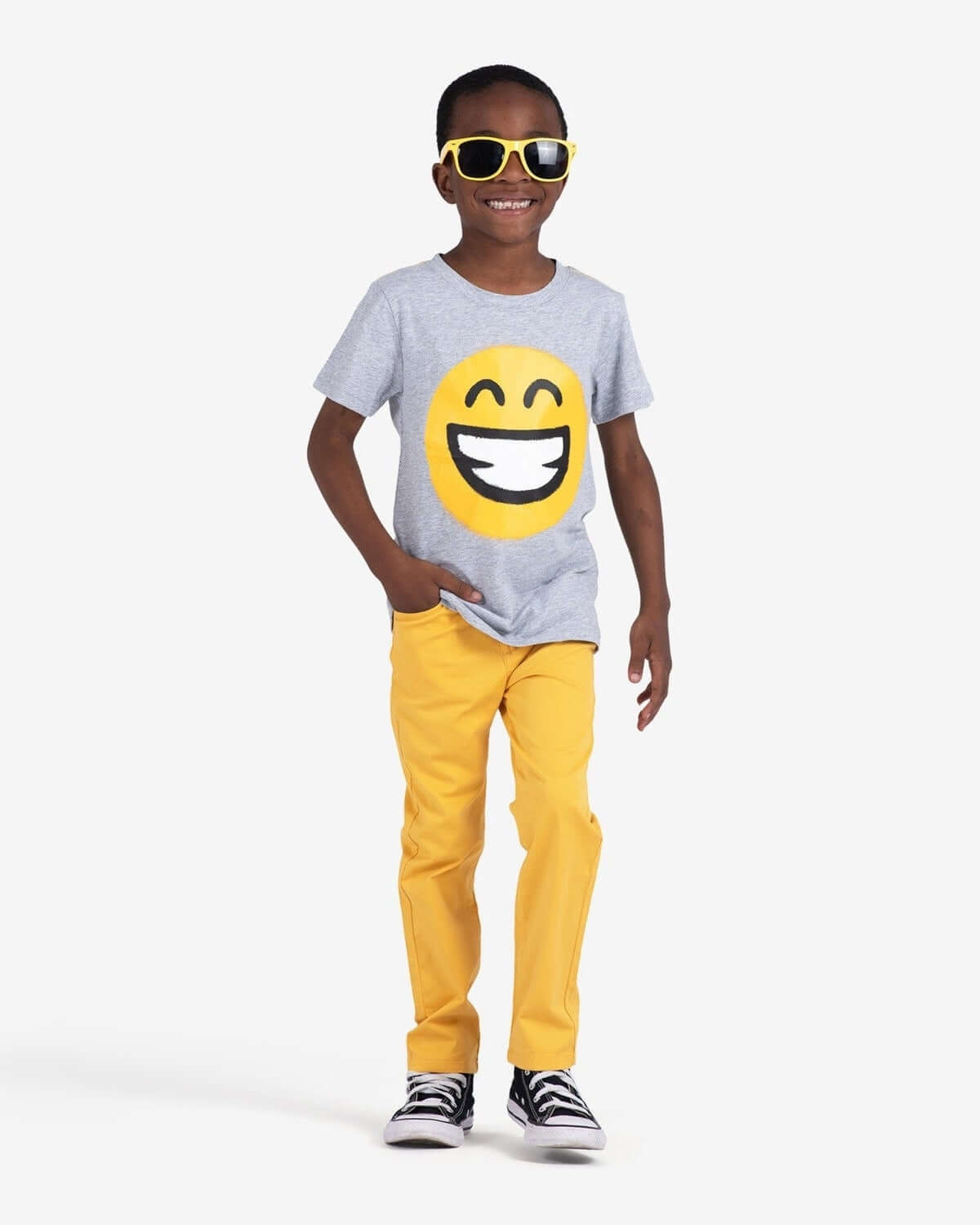A stylish kid rocking a smiley face tee with yellow skinny pants, capturing fun vibes in trendy kids clothes.