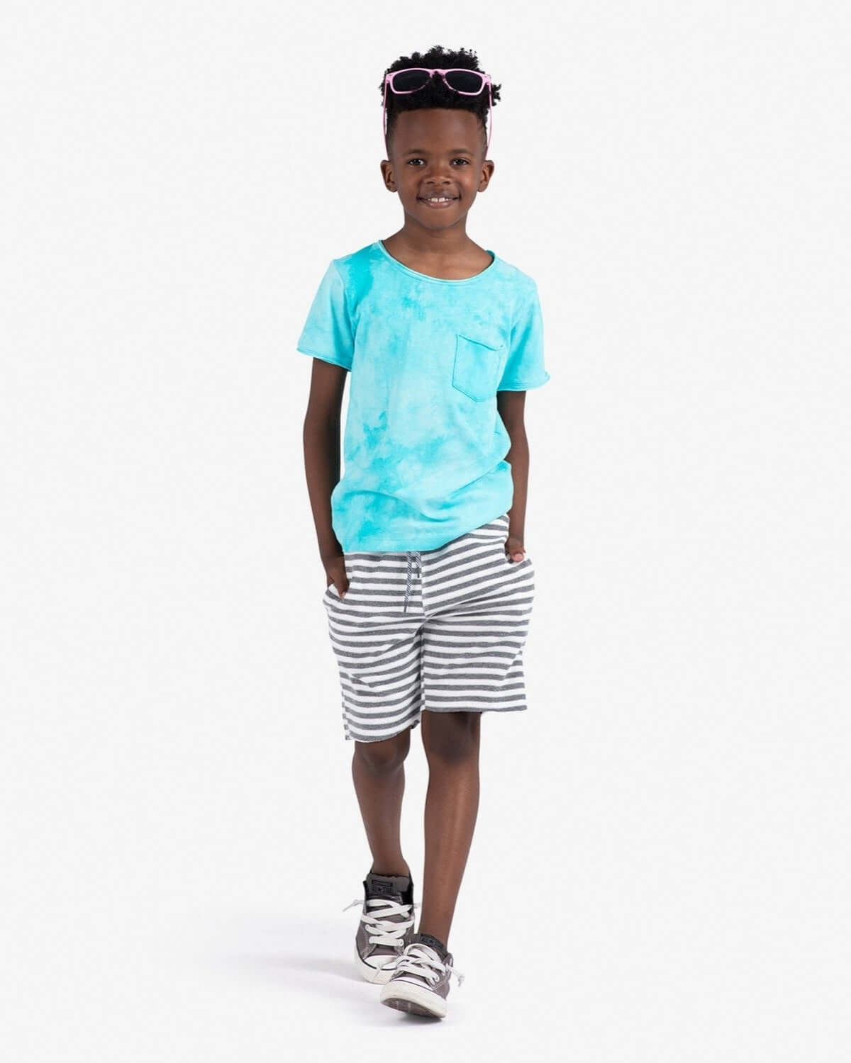 A stylish kid confidently rocking grey stripe terry camp shorts and a vibrant blue tee, ready for summer fun!
