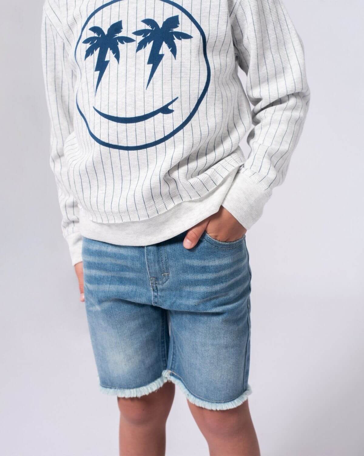 Stylish kid in light wash denim shorts and trendy sweatshirt, ready for back to school fun! Perfect for boys and girls.