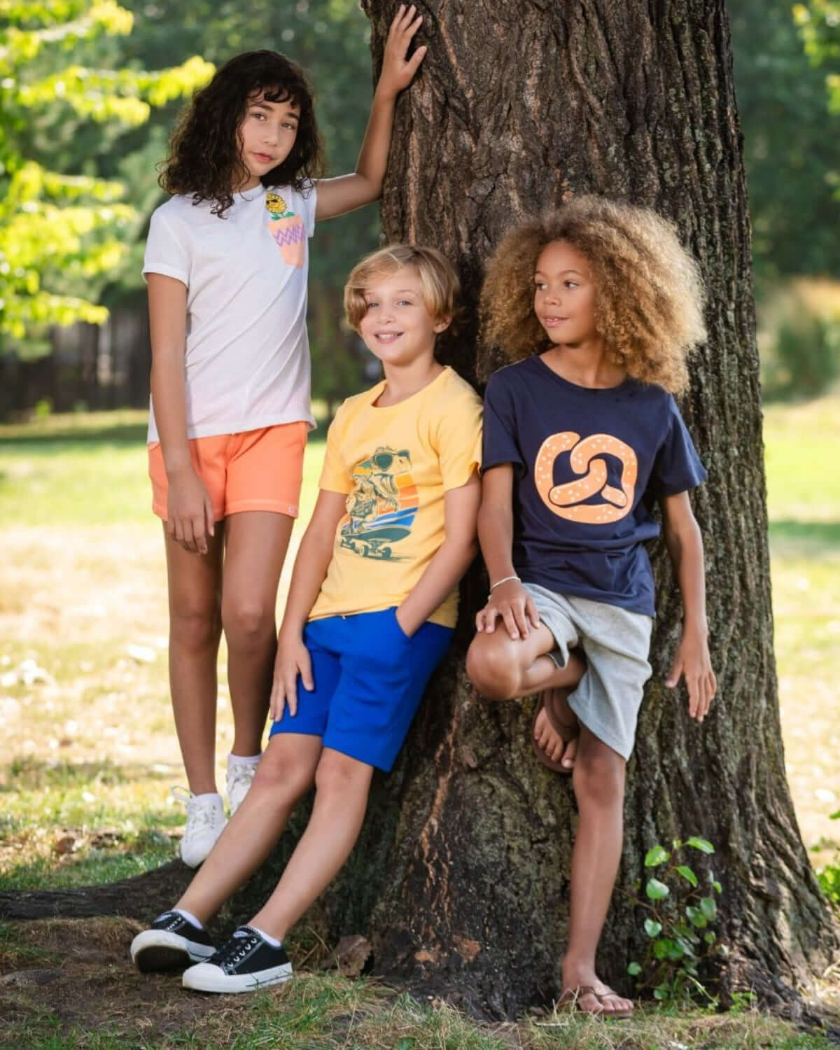 Three trendy kids in vibrant outfits, enjoying a sunlit day outdoors—perfect for back-to-school adventures!