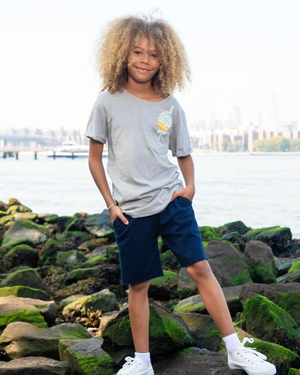 Confident kid enjoying a sunny day in stylish navy blue camp shorts and a light gray tee, ready for summer fun!