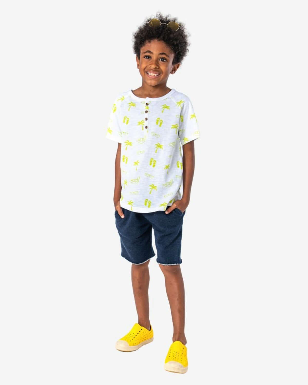 Stylish kid in fun palm-print shirt and navy camp shorts, ready for summer adventures in high-quality kids clothes!
