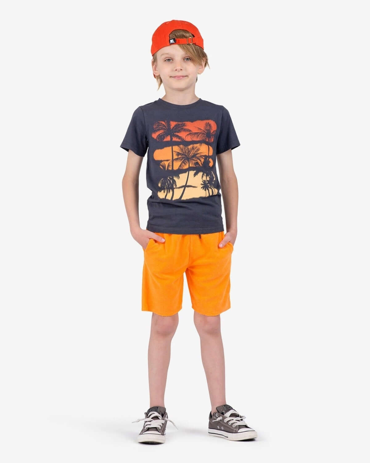 Stylish kid in orange Camp Shorts and graphic tee, ready for summer adventures in high-quality kids clothes.