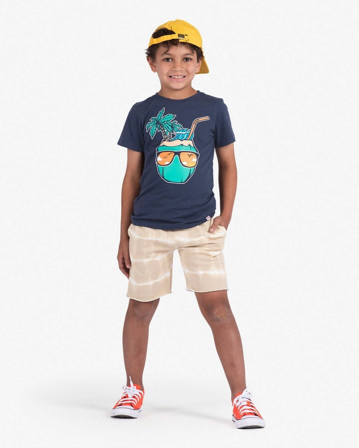 A stylish kid in Sand Stripe Camp Shorts and a fun graphic tee, ready for summer adventures in playful comfort.