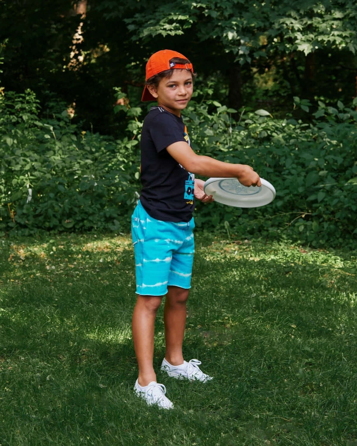 Energetic kid rocking Sea Stripe Camp Shorts, ready for summer fun with a frisbee—stylish and comfy for active play!
