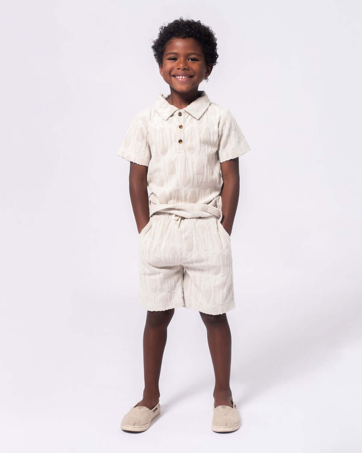 Surfboards Preston Shorts worn by a smiling boy, showcasing a stylish taupe outfit perfect for beach days.