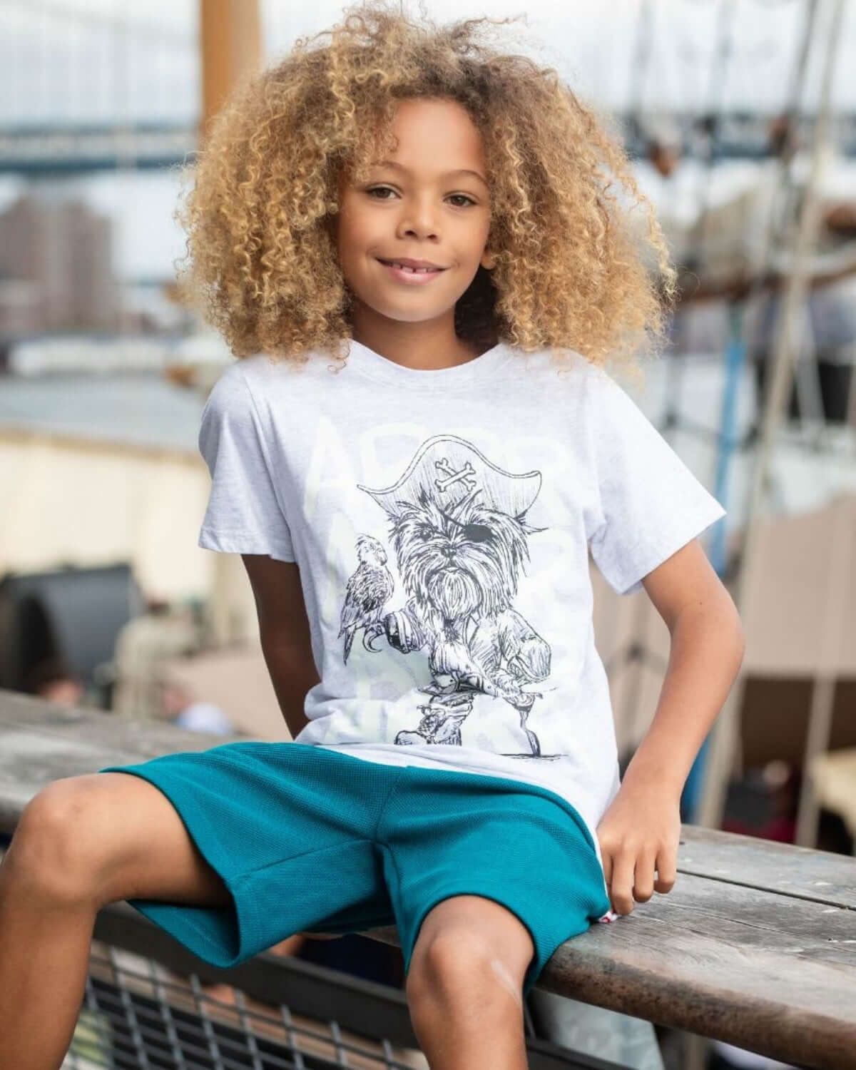 Boy wearing Teal Preston Shorts and a white graphic tee, ready for summer fun.