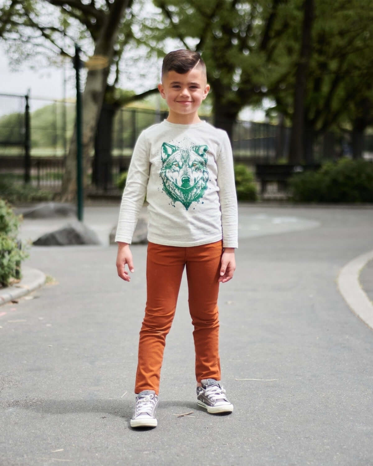 Boy wearing Terracotta Skinny Twill Pants with a wolf graphic tee in a park setting.